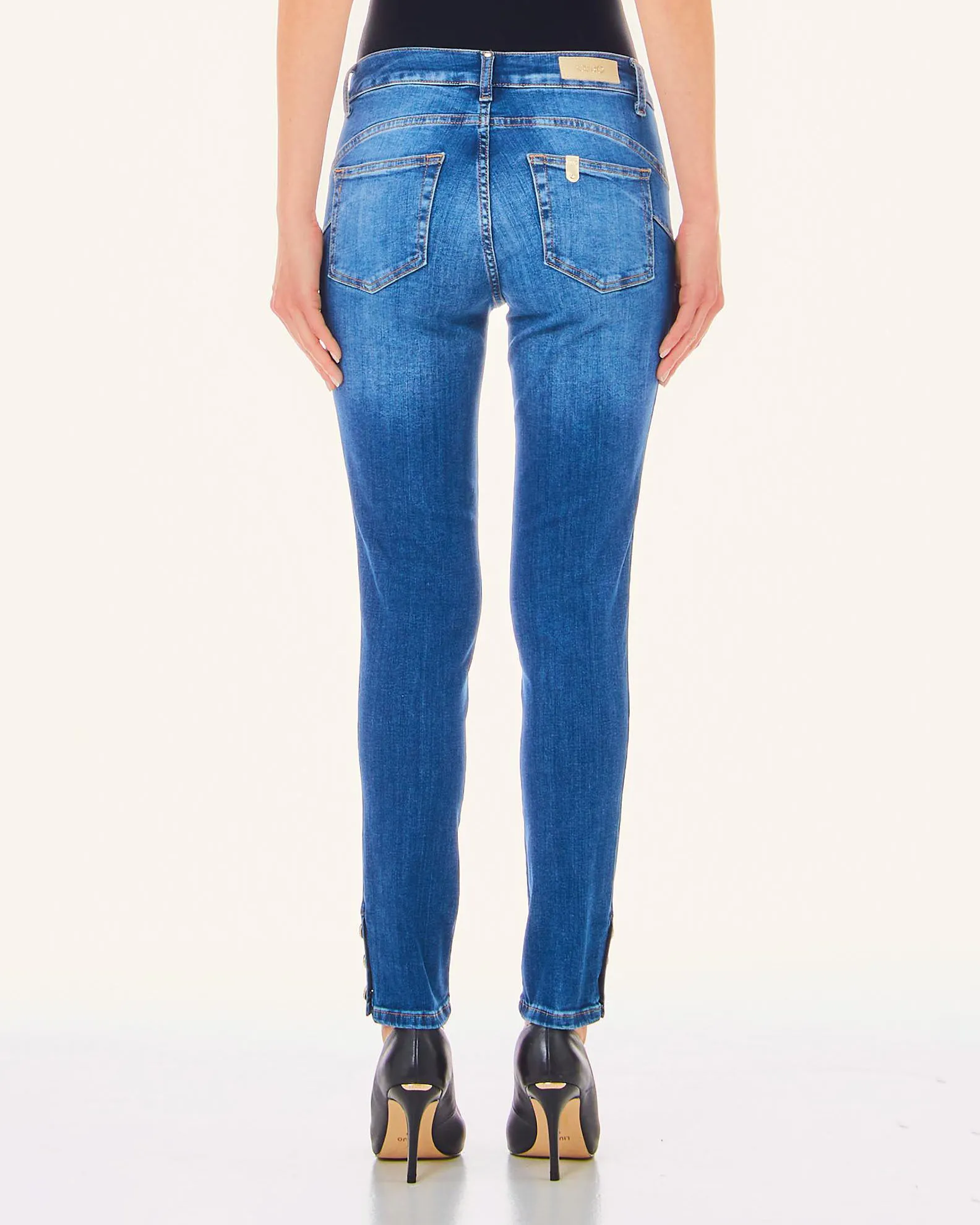 Jeans skinny blu mirato in cotone stretch con bottoni gioiello sugli spacchi laterali al fondo
